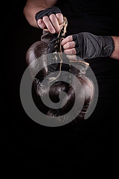 sportsman in black uniform holds old vintage leather boxing gloves