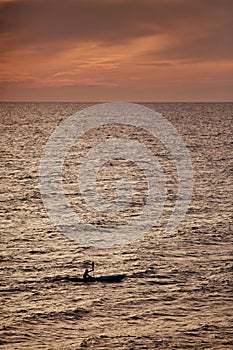 Sportsman on canoe on sunset