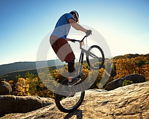 Sportsman cyclist balancing on back wheel on trial bicycle