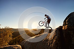 Sportsman cyclist balancing on back wheel on trial bicycle