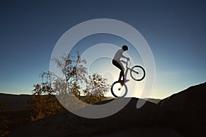 Sportsman cyclist balancing on back wheel on trial bicycle