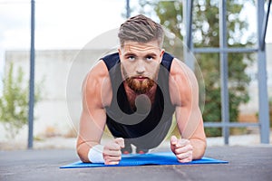 Sportsman doing plank exercise on blue fitness mat during workout