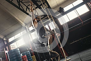 Sportsman doing rope climbing exercise in the cross training gym