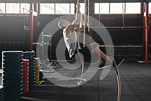 Sportsman doing rope climbing exercise in the cross training gym