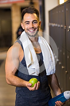 sportsman eating apple after training in lockerroom