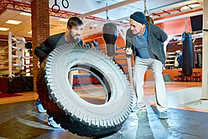 Sportsman flipping tyre with coach near