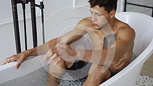 Sportsman gets into a bath with ice cubes