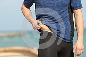 Sportsman hand pinching body fat outdoors