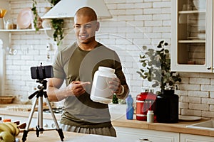 Sportsman holding big pack of dietary protein filming video