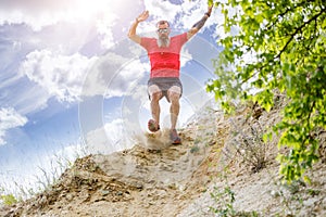 Sportsman jumping from the cliff on trail running