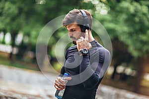 Sportsman listening to music while doing exercising in the park. Fitness, sport, lifestyle concep