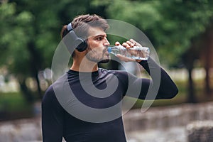 Sportsman listening to music while doing exercising in the park. Fitness, sport, lifestyle concep