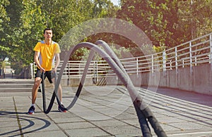 Sportsman making wave movement with battle rope