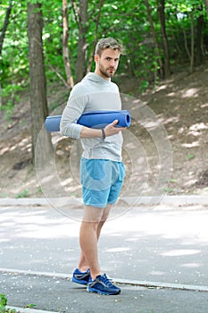 Sportsman man in sportswear keep healthy lifestyle and do sport or fitness workout with yoga mat outdoor