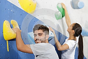 sportsman man and woman climbing wall