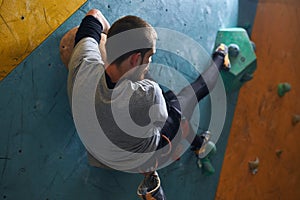 Sportsman moving at artificial rock wall, preparing to extreme mountain ascend