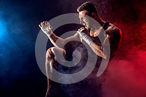 Sportsman muay thai boxer fighting on black background with smoke.
