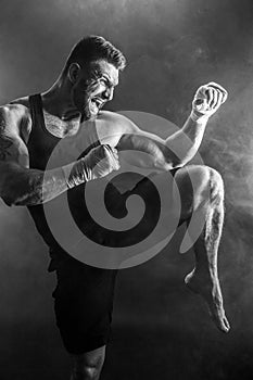 Sportsman muay thai boxer fighting on black background with smoke. photo
