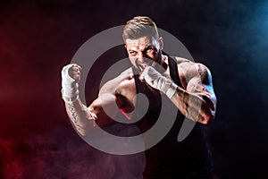 Sportsman muay thai boxer fighting on black background with smoke.