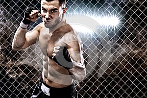 Sportsman muay thai boxer fighting in boxing cage. Background with lights and smoke. Copy Space. Sport concept.
