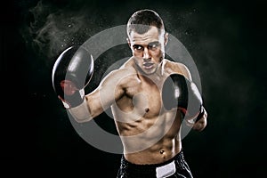 Sportsman muay thai boxer fighting in gloves in boxing cage. Isolated on black background with smoke. Copy Space.