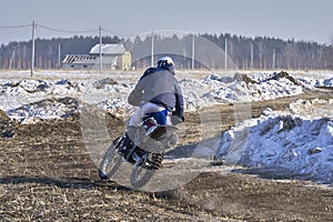 Sportsman racer man fulfills a fast ride on a motorcycle on the road extreme. The race track is very uneven