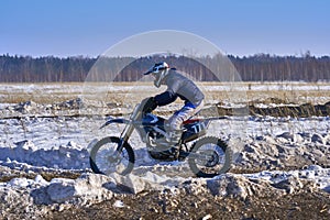 Sportsman racer man fulfills a fast ride on a motorcycle on the road extreme. The race track is very uneven.