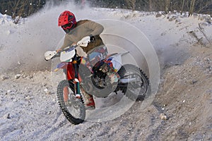 Sportsman racer man fulfills a fast ride on a motorcycle on the road extreme. The race track is very uneven. Photo as the racer p