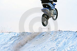 Sportsman racer man fulfills a fast ride on a motorcycle on the road extreme. The race track is very uneven. Photograph of a spor