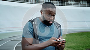 Sportsman reading bad news on smartphone. Sad man using mobile phone outdoors