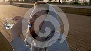 Sportsman is relaxing after running in morning time, drinking clear water