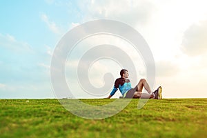 Sportsman resting after sport in the park and looking far away at the sunset