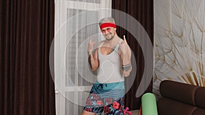 Sportsman retro bearded guy in funny clothes, man showing rock and roll gesture, dancing at home