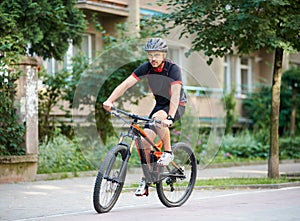 Sportsman riding bike next to old building