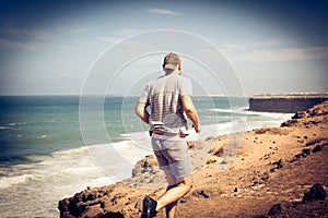 Sportsman running at the beach coast. From back.