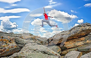 Sportsman running, jumping over rocks in mountain area.