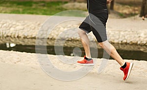 Sportsman running in the park, side view of legs