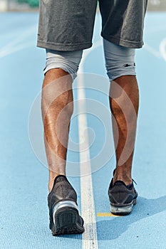 Sportsman`s muscual legs, athlete walking in the stadium