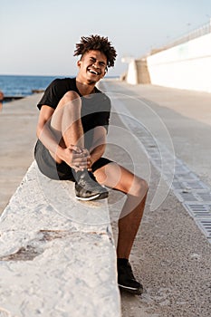 Sportsman sitting with pain in leg outdoors on the beach