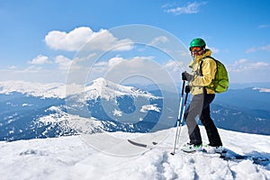 Sportsman skier on skis on background of blue sky and highland landscape. Winter skiing concept.