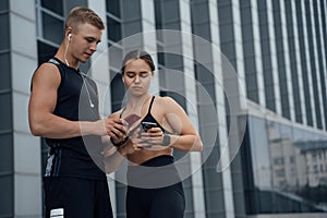 Sportsman and sportswoman with cellphones sharing content
