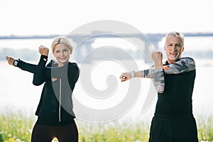 Sportsman and sportswoman looking at camera while warming up in park