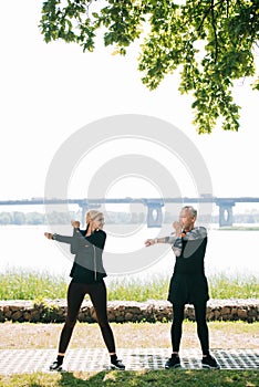 Sportsman and sportswoman warming up and looking at each other in park