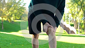 Sportsman stretching before outdoor activities in park. Young Caucasian man standing outside on summer sunny day and