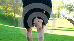 Sportsman stretching before outdoor activities in park. Young Caucasian man standing outside on summer sunny day and