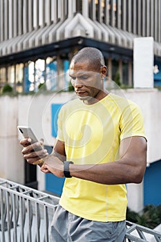 Sportsman synchronizing mobile phone and smartwatch to do sports in the city