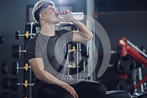 Sportsman in t-shirt drinking water in the fitness gym, Handsome sporty resting