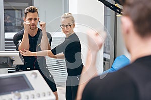 Sportsman teached by personal trainer in front of mirror