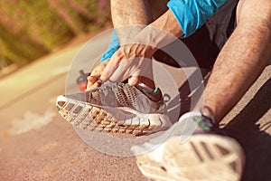 Sportsman tie shoelaces on his running shoes in the park