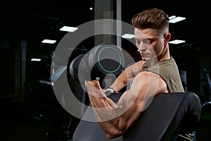 Sportsman training biceps with dumbbell.